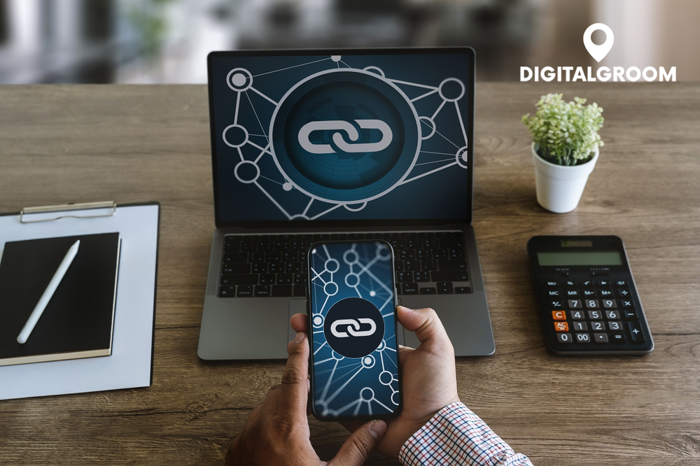 Ein Laptop und ein Smartphone, die ein Netzwerksymbol mit einer Verknüpfung anzeigen, auf einem Schreibtisch mit Bürobedarf. Das Bild betont die Bedeutung von Backlink-Verzeichnissen für die SEO-Strategie. Digitalgroom-Logo im Hintergrund.